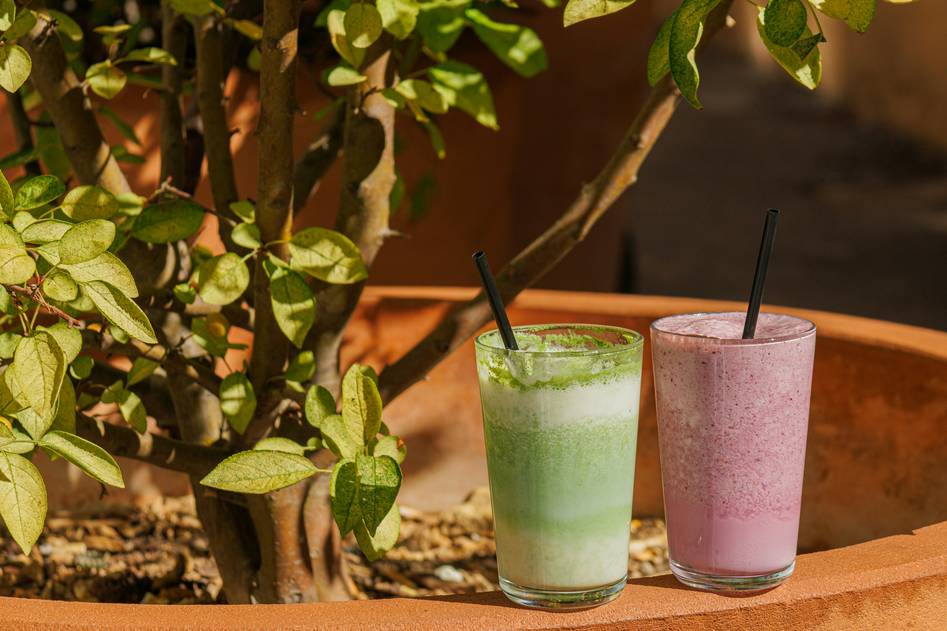 A woman enjoying a vibrant green organic shake in a sunny kitchen